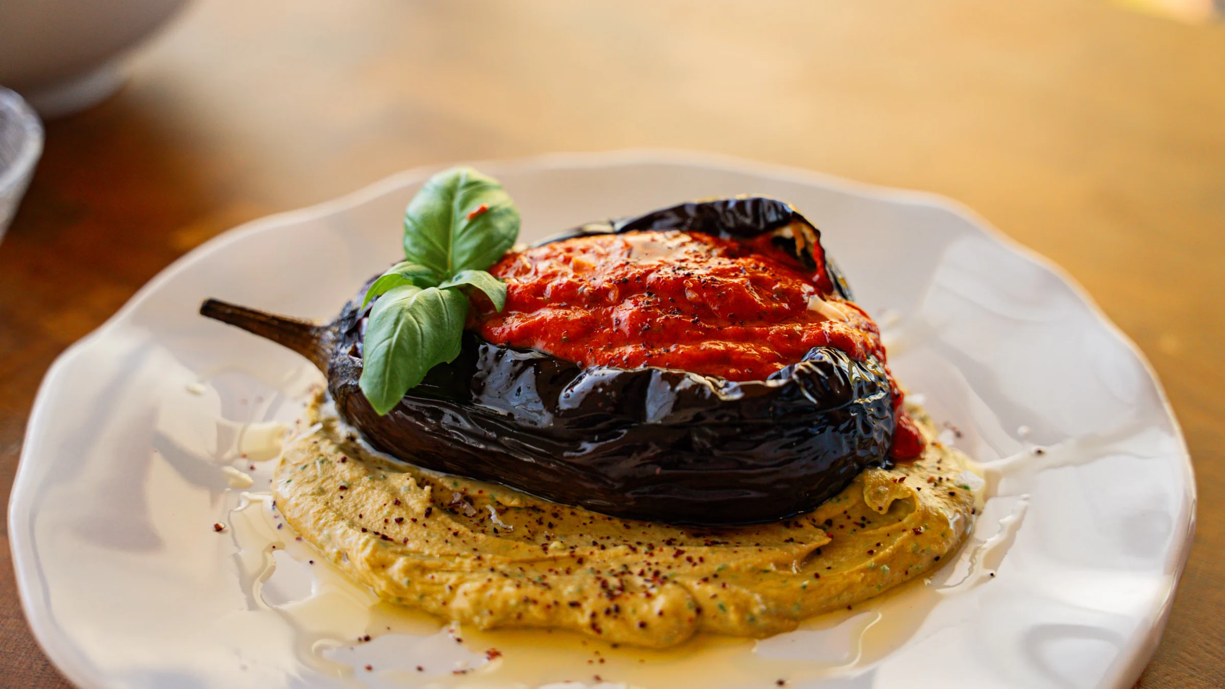Roasted aubergine served with creamy wild garlic hummus and smoky tomato pepper confit.